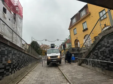 En gångväg mellan kaklade väggar upp från tunneln, med en vit liftbil i gången och ljusslingor uppspända över gatan.
